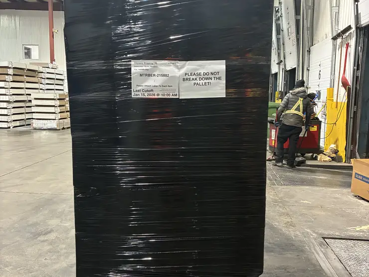 Shrink-wrapped pallet labelled for shipment on a loading dock