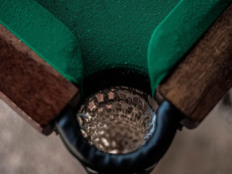 Poche de coin d’une table de billard, avec bande de bois et tapis vert